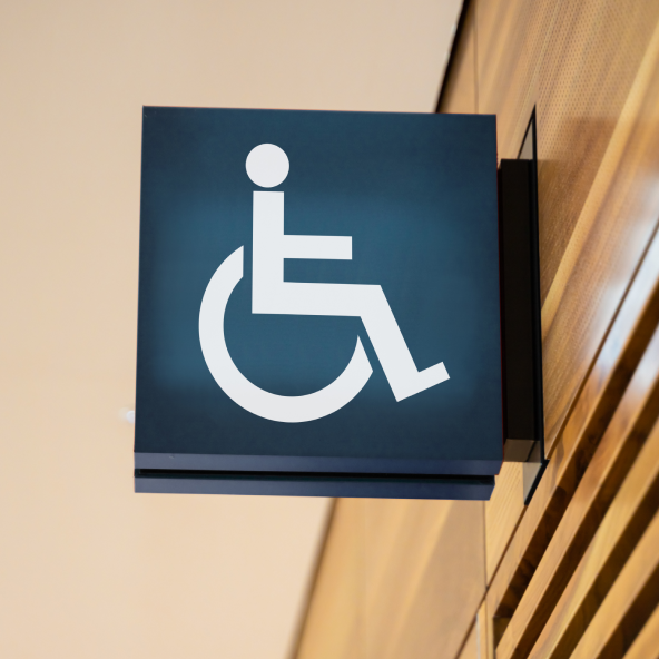 Znak wiszący na ścianie przedstawiający osobę na wózku